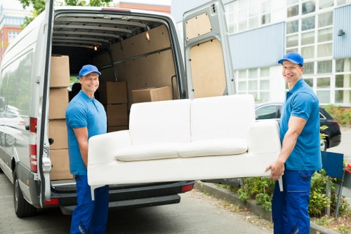Team member handling moving boxes safely with a removal van in the background